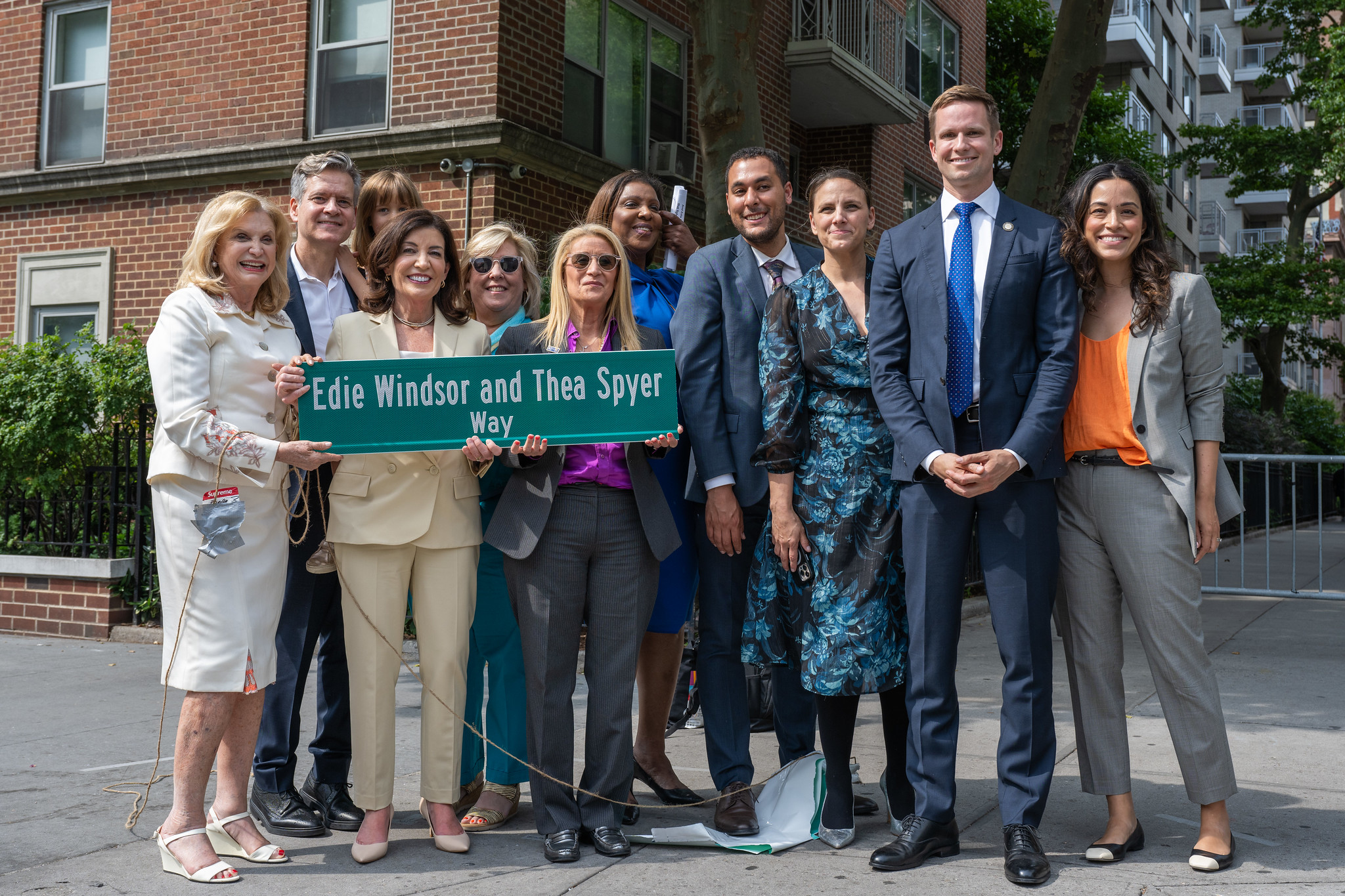 Governor Hochul, Judith Kasen Windsor and AG Letitia James pose with NY elected officials and a copy of the new street sign.